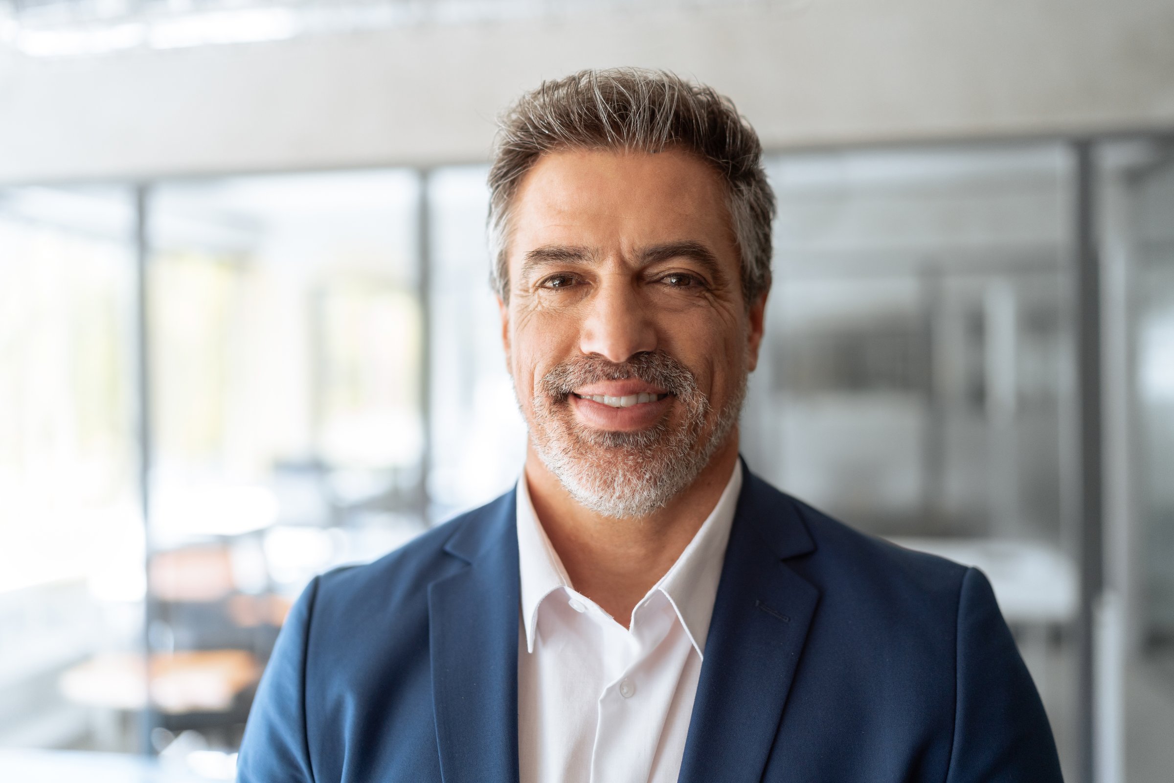Headshot executive confident senior business man specialist smiling at camera. Closeup friendly portrait of grey haired professional boss, leader, ceo, male bank manager businessman in suit in office