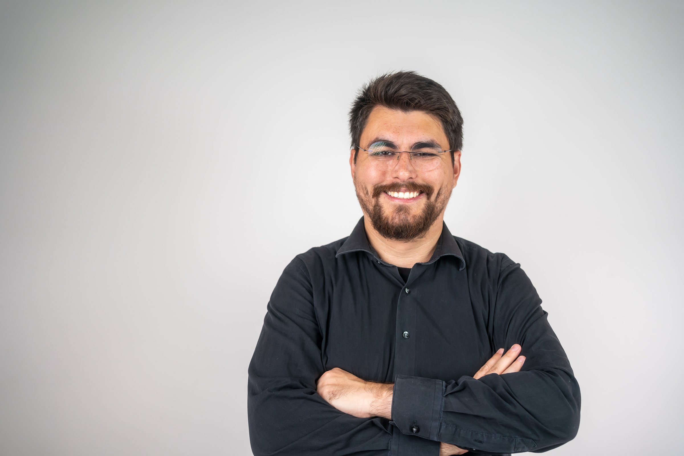 Portrait of a happy young casual man standing. Portrait of happy fashionable handsome man in yellow t-shirt and glasses crossing hands and smiling